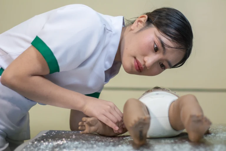 A student wraps an infant manikin