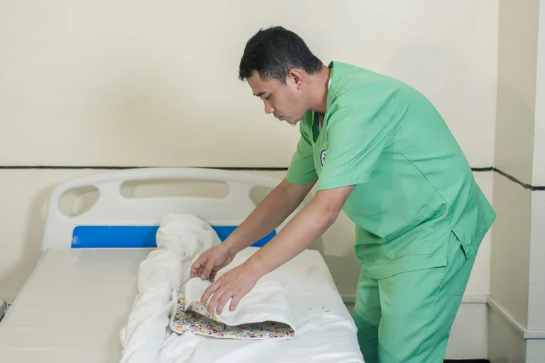 A student smooths the sheets on a bed